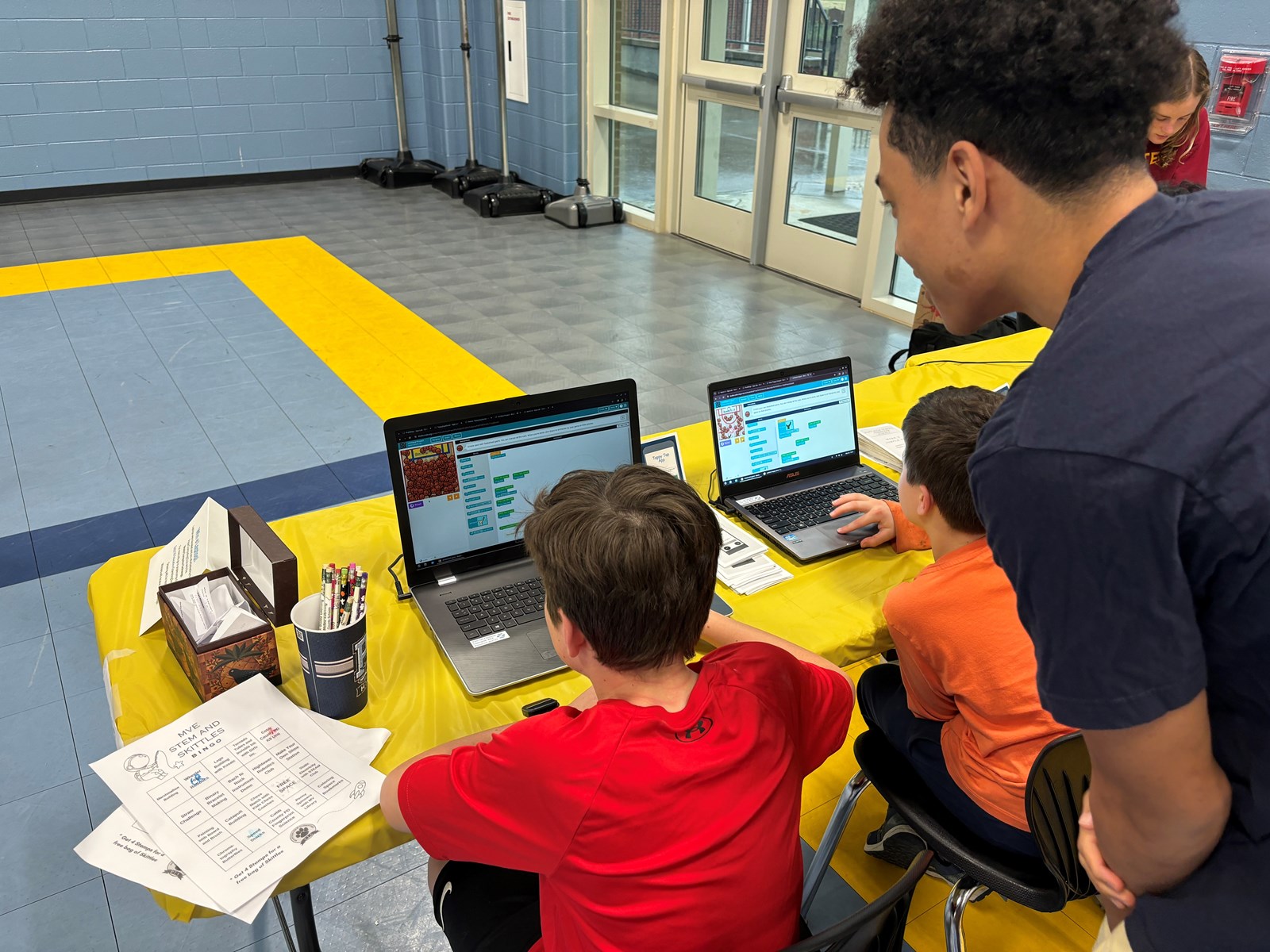 computer science student helping elementary students
