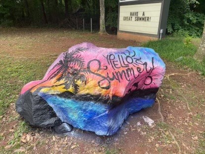 picture of painted rock outside of school. The rock says Hello Summer!