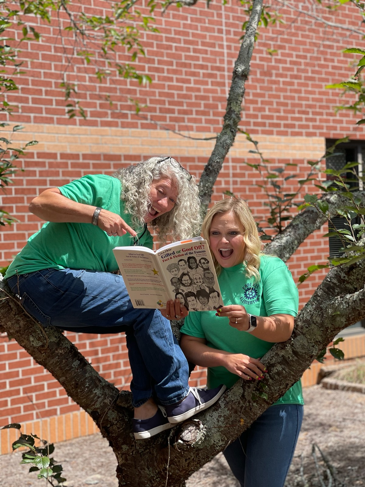 Two Chalker staff members in tree looking at a book